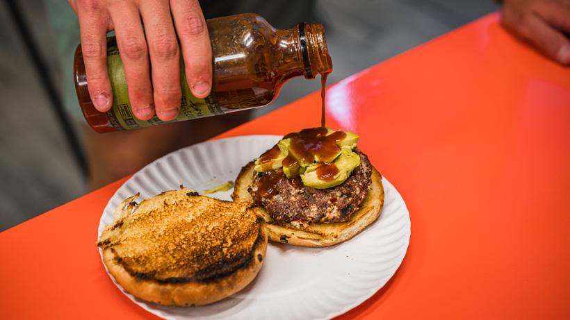 Adding traeger sweet and heat bbq sauce to burger